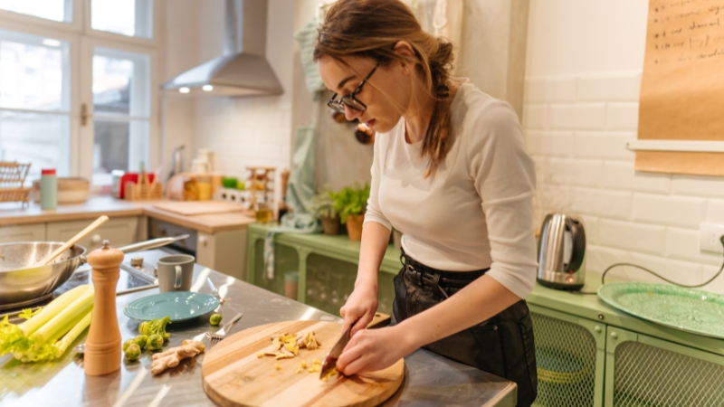 A woman chopping vegetables in the kitchen while preparing healthy study snacks in advance