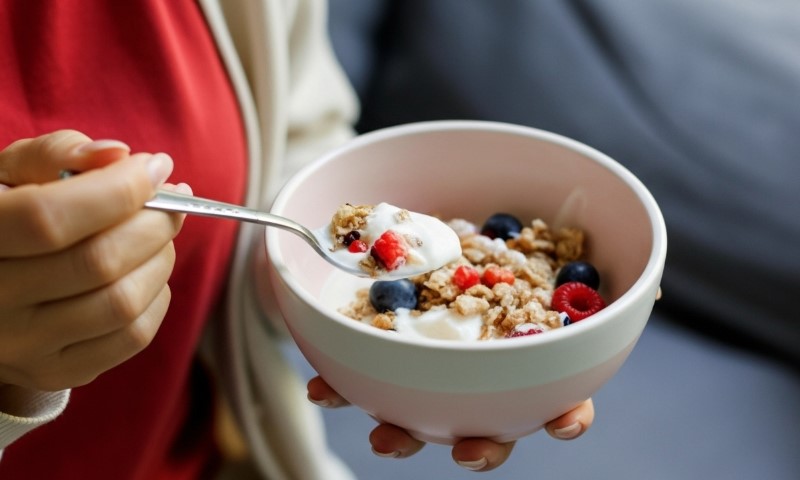 A woman holds a bowl of cereal topped with yogurt and fresh berries