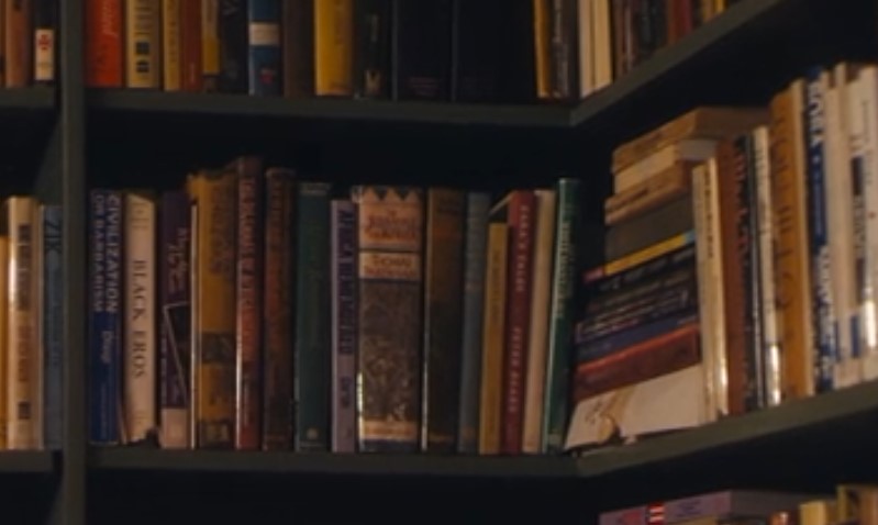 A wooden bookshelf filled with a variety of colorful books arranged neatly from top to bottom