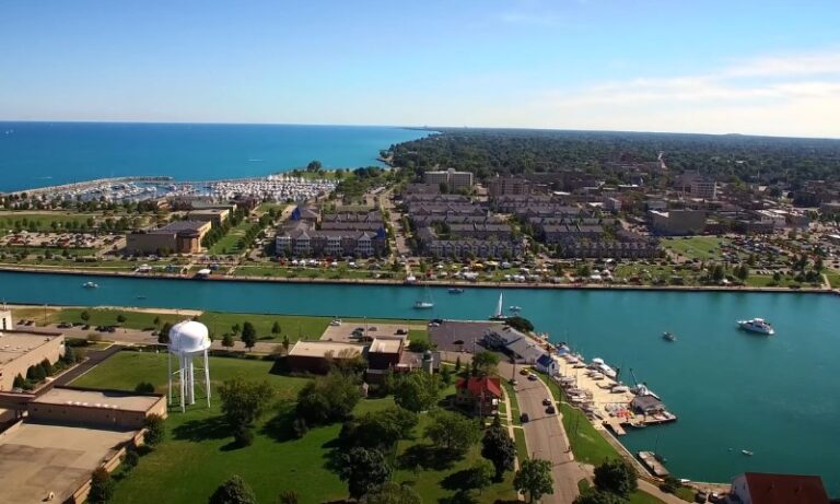 Aerial view of a lakeside city with a vibrant blue lake, marina with docked boats