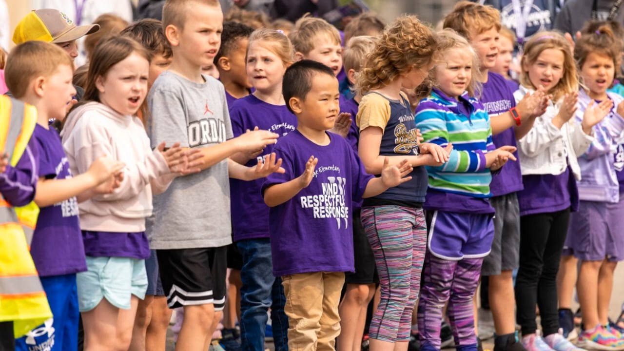 Group of young children standing together outdoors, clapping and participating in an activity