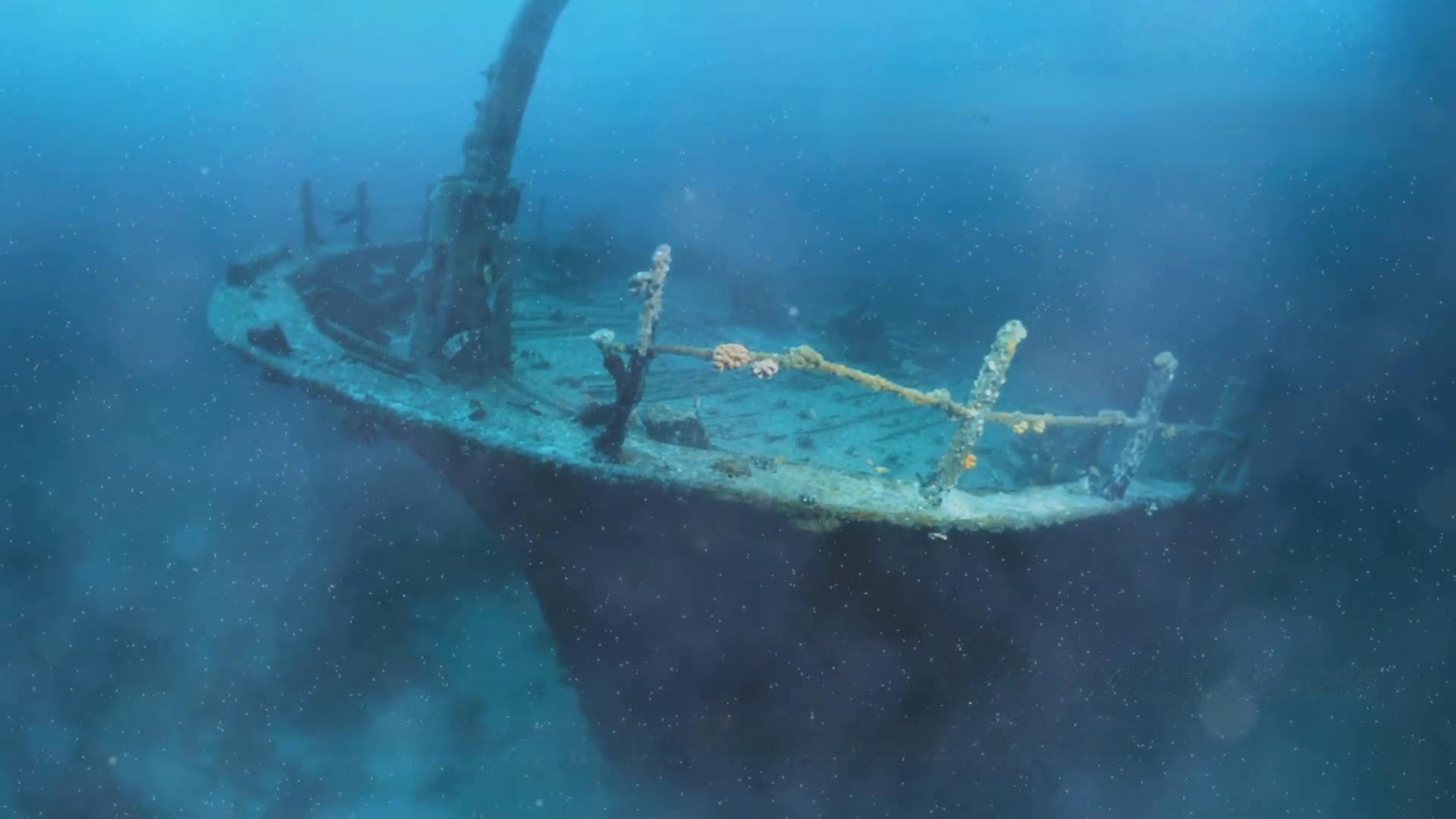 Underwater view of a sunken schooner’s bow resting upright on the lakebed in deep blue water