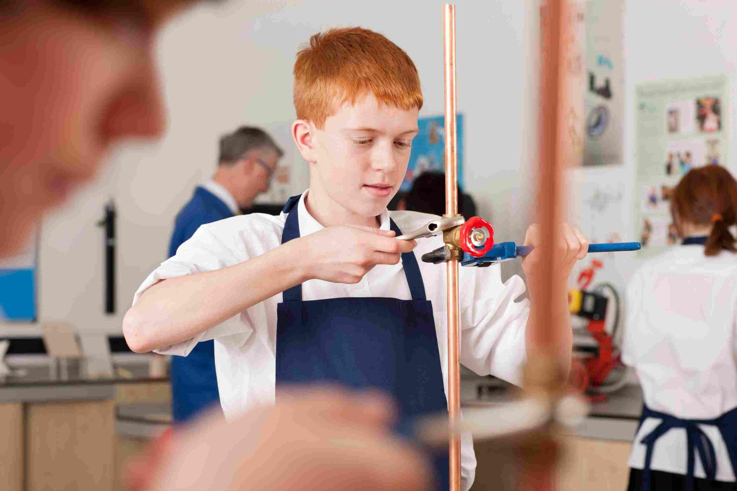 Student working with copper piping and tools in a classroom workshop